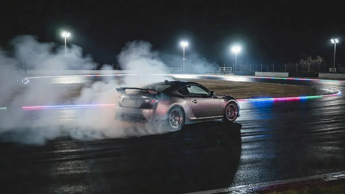 Nissan drift car cornering under neon lights on a closed circuit at night during a drifting lessons Tokyo session in Japan