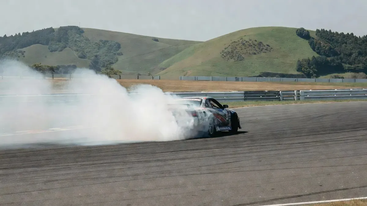 Rear-wheel-drive JDM car sliding sideways in tire smoke on a closed circuit during drifting lessons Tokyo near Minami Chiba, Japan